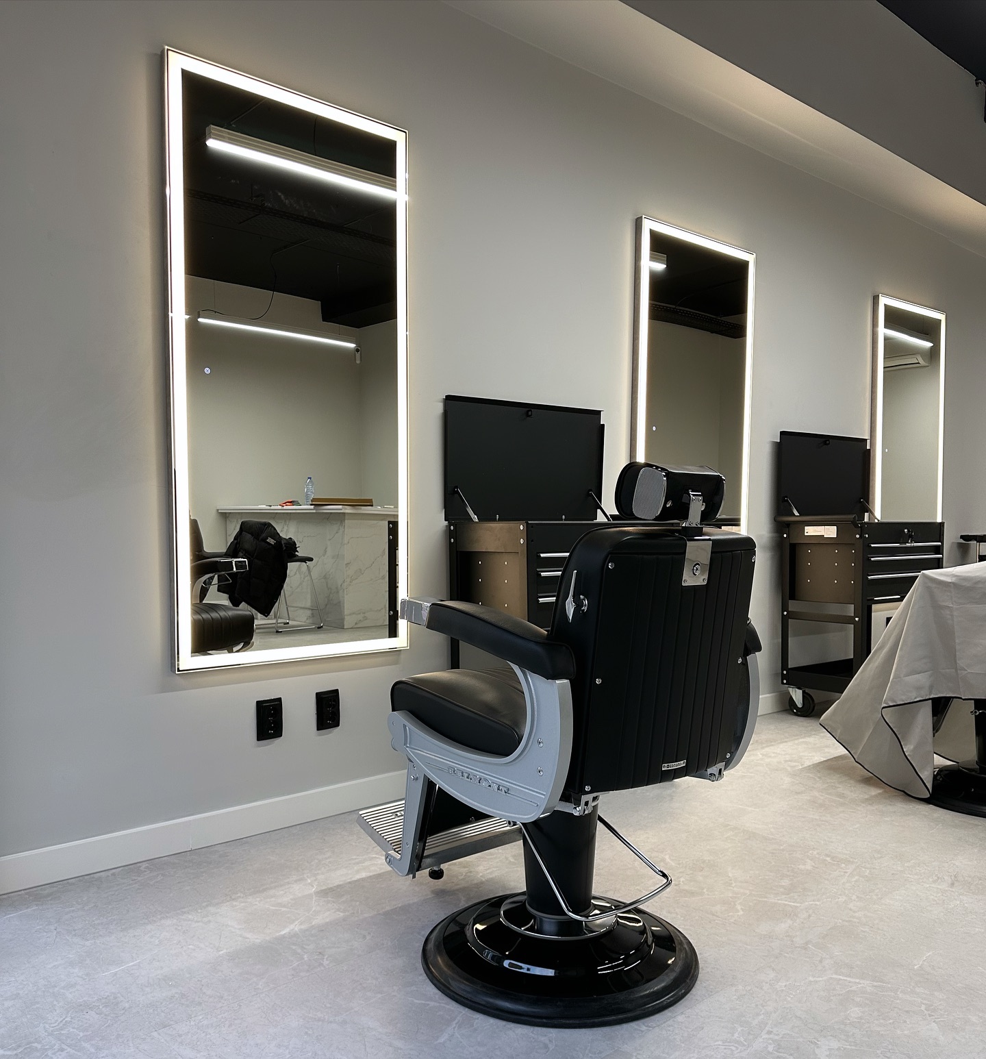 Interieur van Excellence Hair: zwarte kappersstoel voor hoge spiegels met ledverlichting
